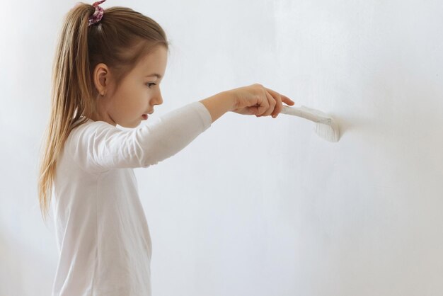 bambina bionda con rullo di pittura murale durante la ristrutturazione domestica