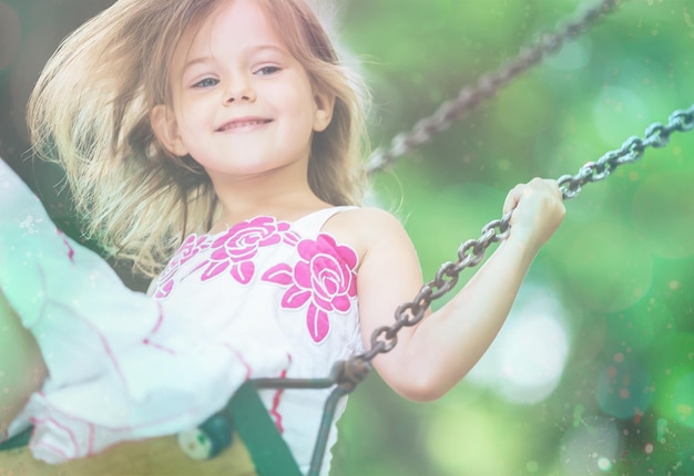 Bambina bionda divertendosi su un'altalena