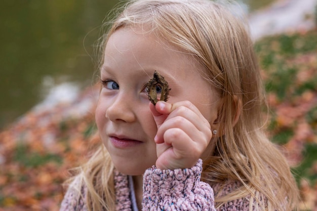 Bambina bionda sorridente che gioca nel parco autunnale Vista dall'alto