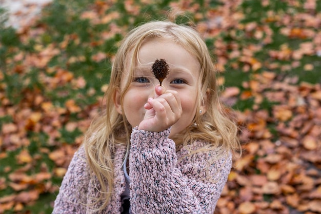 Bambina bionda sorridente che gioca nel parco autunnale Vista dall'alto