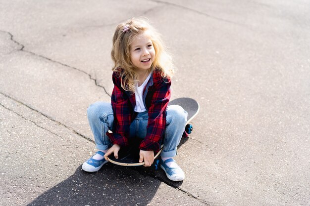 Bambina bionda su uno skateboard in città.
