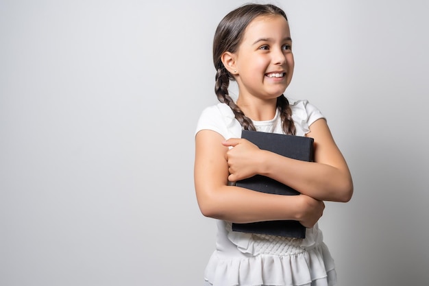 Bambina bruna che legge un libro isolato su uno sfondo bianco.