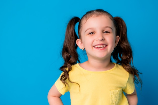 bambina bruna su sfondo blu, sorridente