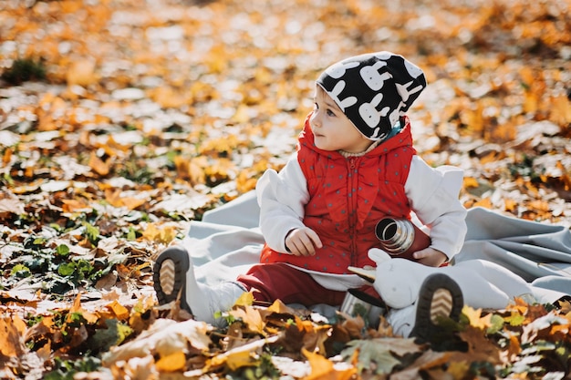 Bambina carina beve il tè da un thermos nel parco autunnale carino bambino bambino con thermos