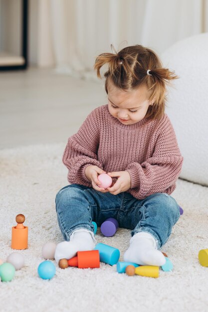 Bambina carina che gioca a casa con giocattoli in legno eco Bambino felice che taglia frutta e verdura con un coltello giocattolo Il bambino che gioca a giochi educativi