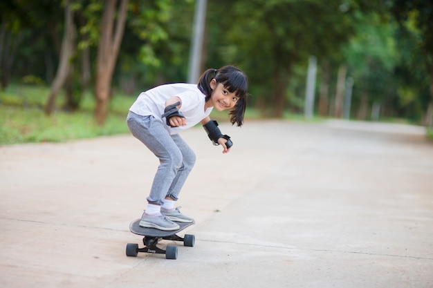 Bambina carina che gioca a skateboard o surf skate nello skate park