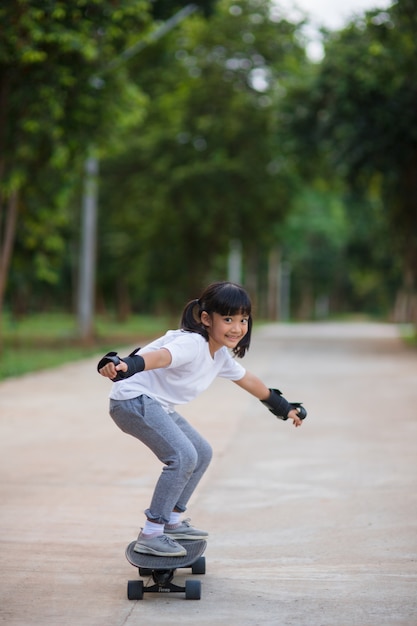 Bambina carina che gioca a skateboard o surf skate nello skate park