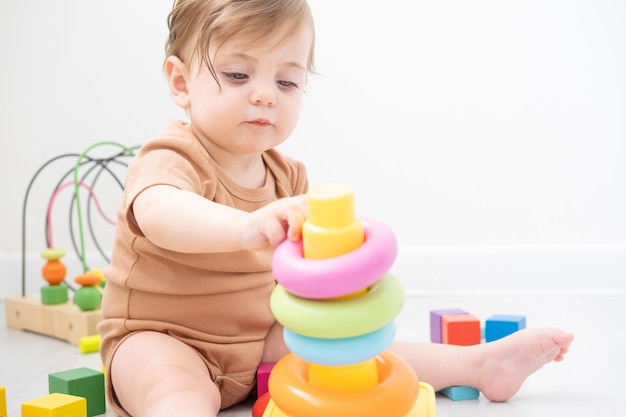 bambina carina che gioca con la piramide e i giocattoli di legno a casa lo sviluppo dei primi bambini
