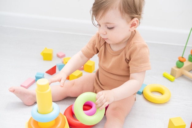 bambina carina che gioca con la piramide e i giocattoli di legno a casa lo sviluppo dei primi bambini