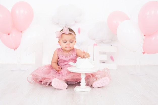 bambina carina che mangia la torta di compleanno e festeggia il suo primo compleanno