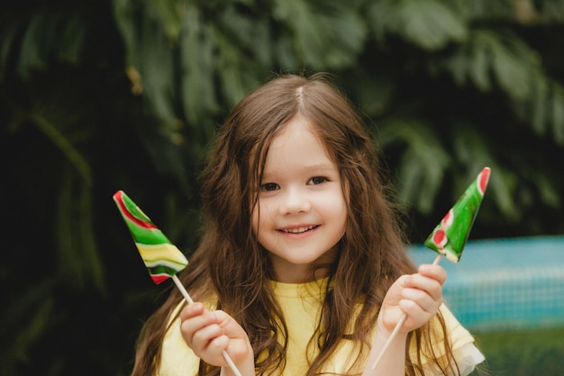 Bambina carina che mangia un lecca-lecca a forma di anguria Bambino con lecca-lecca nel giardino botanico