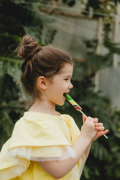 Bambina carina che mangia un lecca-lecca a forma di anguria Bambino con lecca-lecca nel giardino botanico