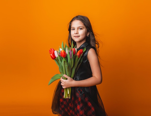 Bambina carina con in mano un mazzo di tulipani su sfondo giallo Buona festa della donna Posto per testo Emozioni vivide 8 marzo