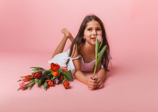 Bambina carina con in mano un mazzo di tulipani su sfondo rosa Buona festa della donna Posto per il testo Emozioni vivide 8 marzo