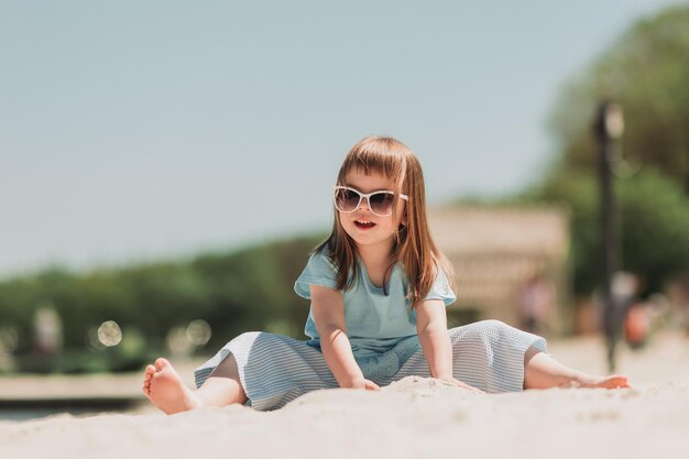 bambina carina in abito blu che paga sulla spiaggia