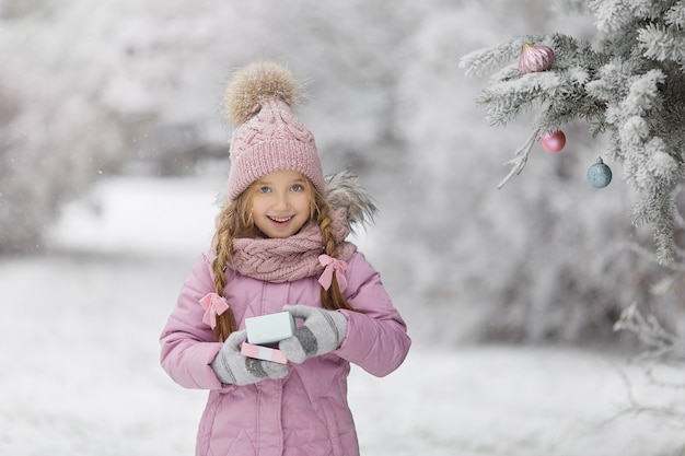 Bambina carina in inverno per strada prima del nuovo anno nella neve