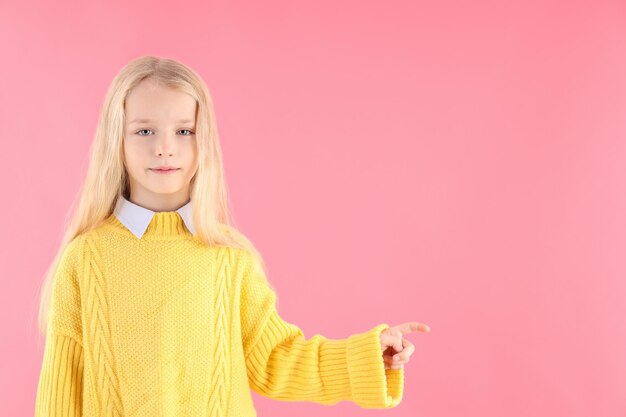 Bambina carina in maglione su sfondo rosa