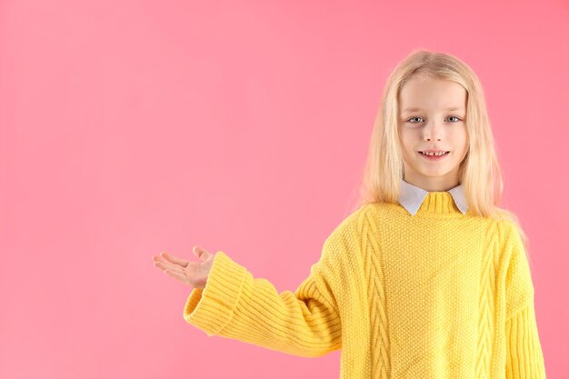 Bambina carina in maglione su sfondo rosa