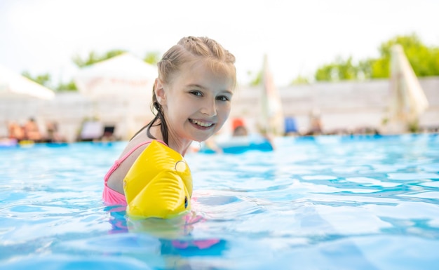 Bambina carina in piscina sorridente e con indosso costumi da bagno colorati bellissimo bambino che si gode l'estate...