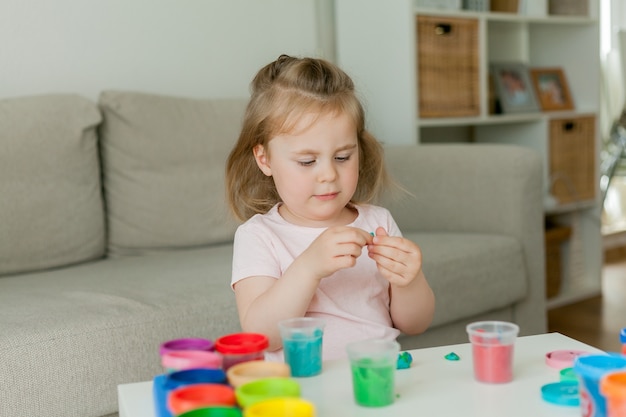 Bambina carina scolpisce dalla plastilina colorata.