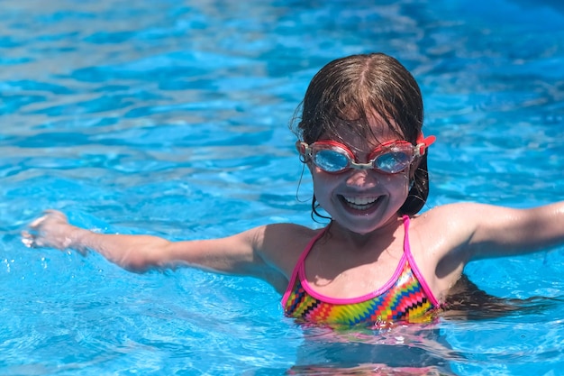 Bambina carina sorridente con gli occhiali in piscina in una soleggiata giornata estiva Divertimento in spiaggia per bambini