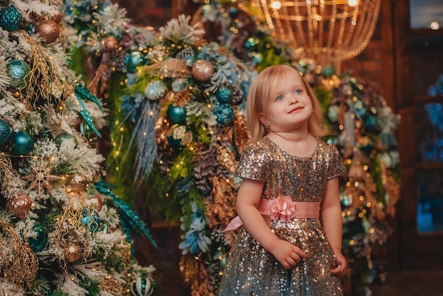 bambina carismatica in un vestito luccicante sullo sfondo delle decorazioni natalizie