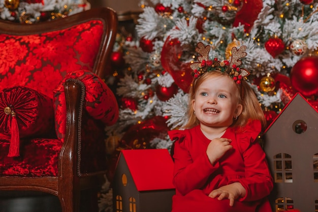 bambina carismatica in un vestito rosso sullo sfondo delle decorazioni natalizie