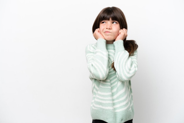 Bambina caucasica isolata su sfondo bianco frustrata e che copre le orecchie