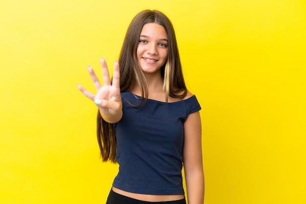 Bambina caucasica isolata su sfondo giallo felice e contando quattro con le dita