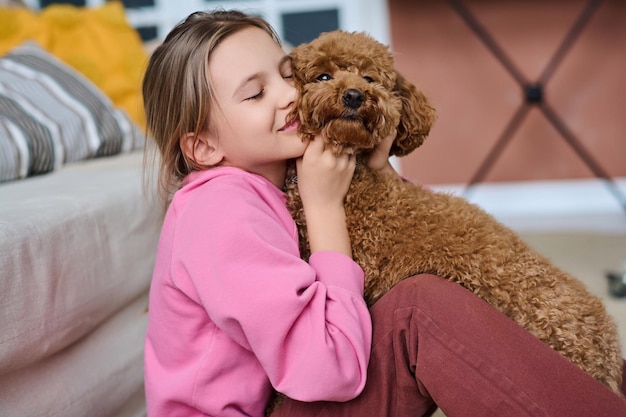 Bambina che abbraccia il suo simpatico cane e gioca con esso nella stanza di casa