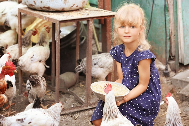 Bambina che alimenta i polli in fattoria