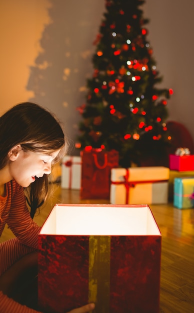 Bambina che apre un regalo di Natale incandescente