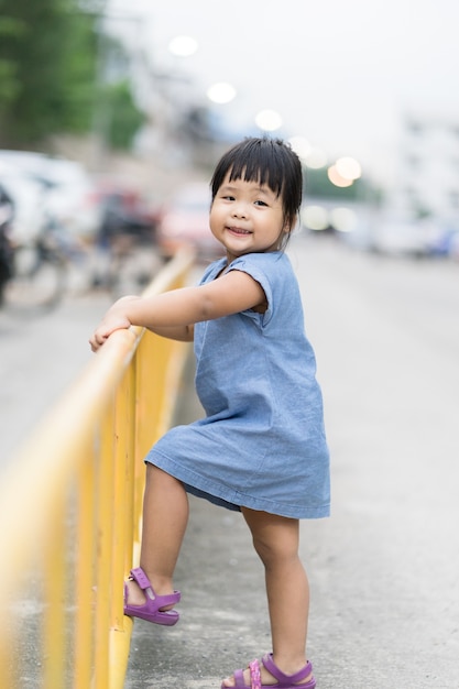 Bambina che arrampica fencein giallo il parco