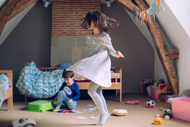 Bambina che balla con la felicità e che gioca con suo fratello a casa