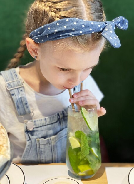 Bambina che beve mojito analcolico in un caffè