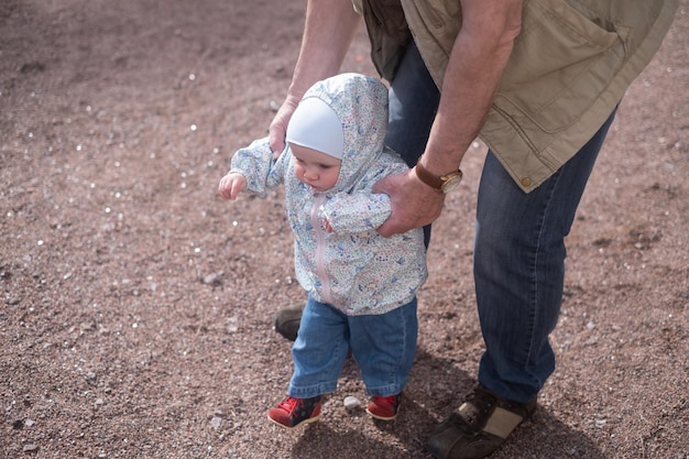 Bambina che cammina all'aperto con l'uomo Il nonno aiuta la nipote a camminare