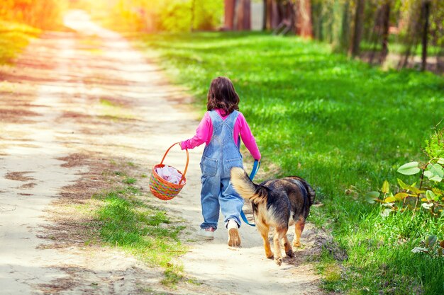 Bambina che cammina con il cane sulla strada torna alla telecamera