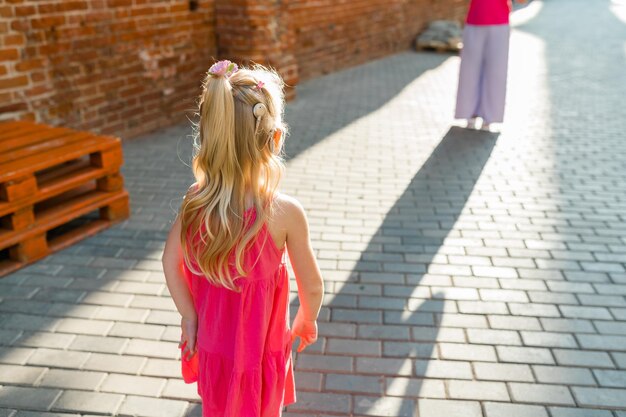 Bambina che cammina e si diverte all'aperto con l'impianto cocleare sulla testa, apparecchio acuto uditivo e trattamento