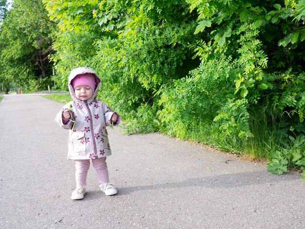 Bambina che cammina nel parco con un dente di leone in mano