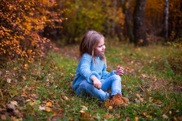 bambina che cammina nella foresta di autunno in vestiti blu