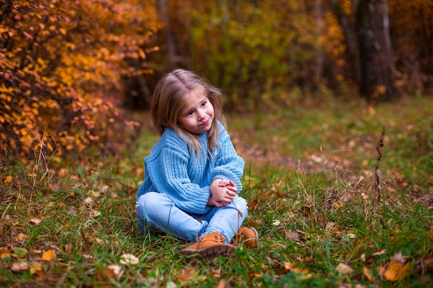 bambina che cammina nella foresta di autunno in vestiti blu