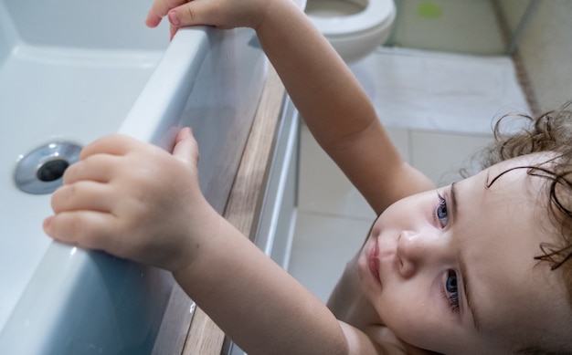 Bambina che cerca di raggiungere il lavandino del bagno.