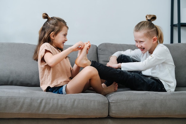 Bambina che cerca di solleticare i piedi dei ragazzi, entrambi ridono sulla vista laterale del divano