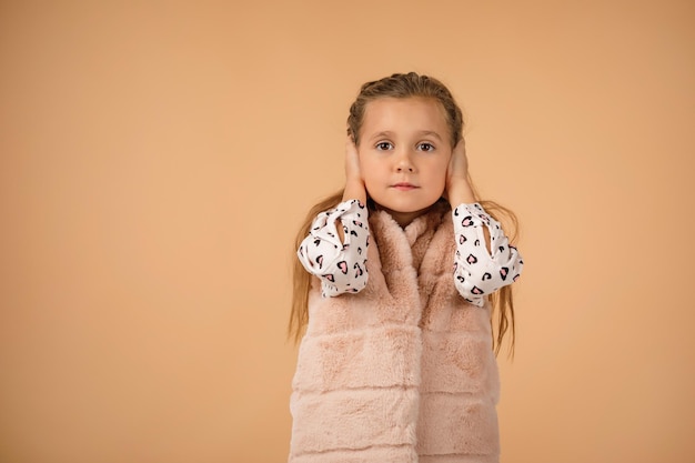 Bambina che copre il suo orecchio con la mano