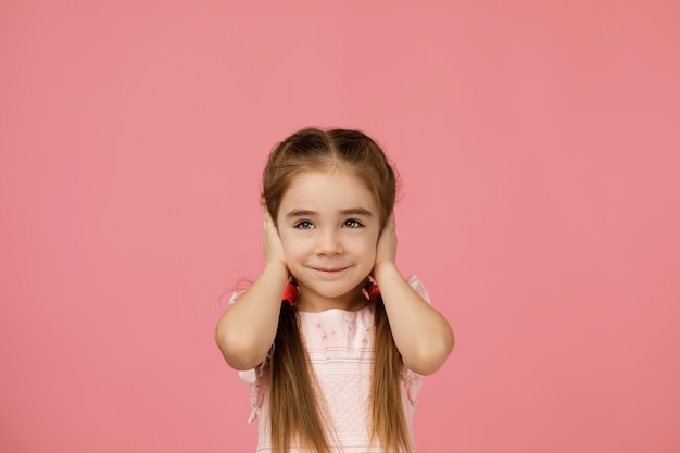 Bambina che copre il suo orecchio con la mano