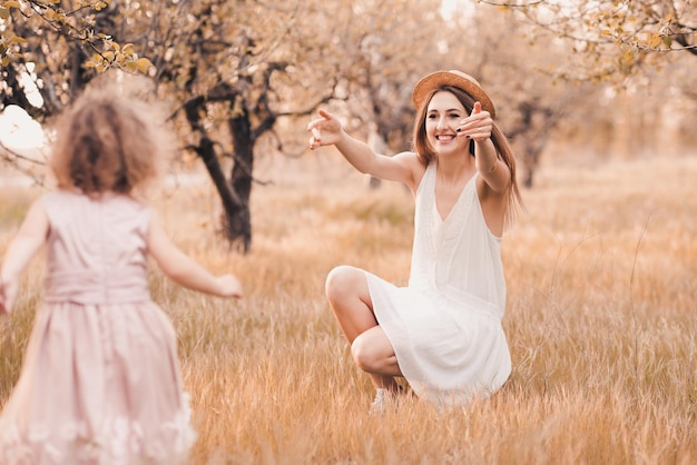 Bambina che corre verso la madre sorridente felice nel prato all'aperto