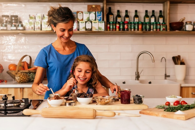 Bambina che cucina con sua madre in cucina. Concetto di chef infantile.