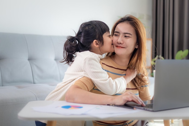 Bambina che dà un bacio a sua madre mentre lavora da casa