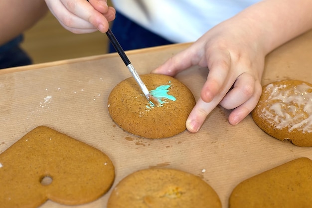 Bambina che decora i biscotti allo zenzero con glassa e zucchero a velo L'assistente della mamma