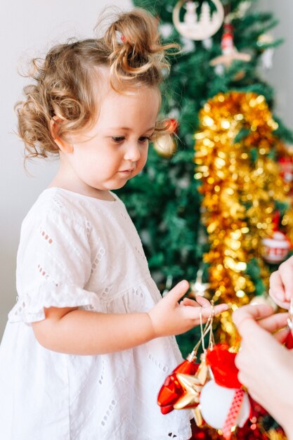 Bambina che decora l'albero di Natale con il genitore